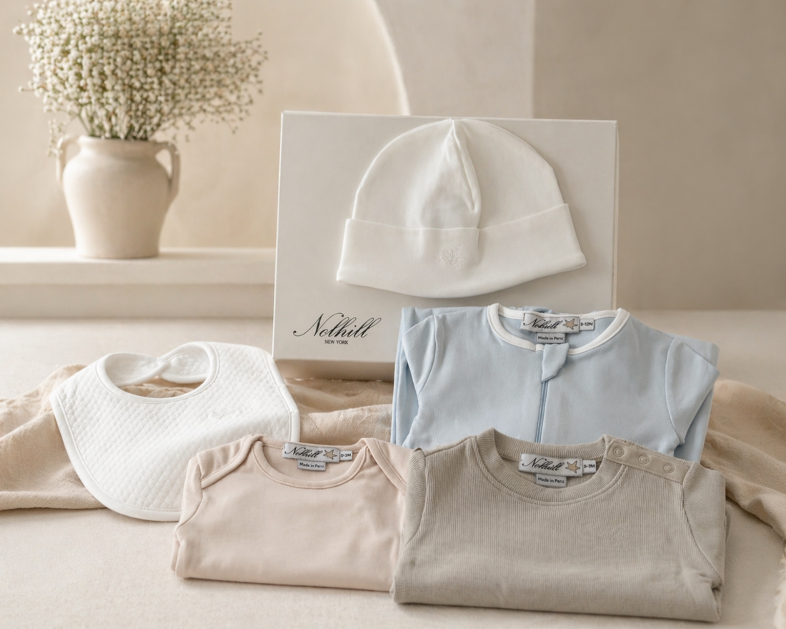 Nolhill L'Essentiel newborn capsule wardrobe flat-lay including Pima cotton bodysuit, romper, layette set, beanie and bib